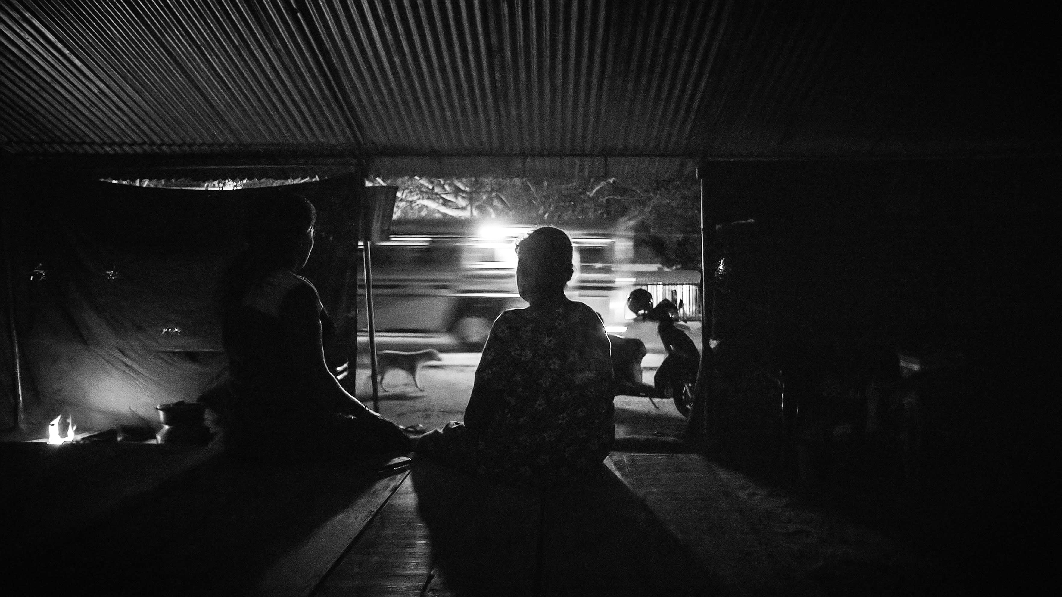 Women sitting in dark shed with bus passing