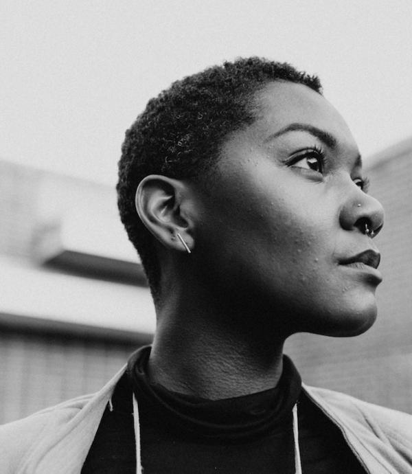 Black woman portrait with a building in the background.