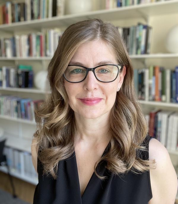 woman in black in front of bookshelves