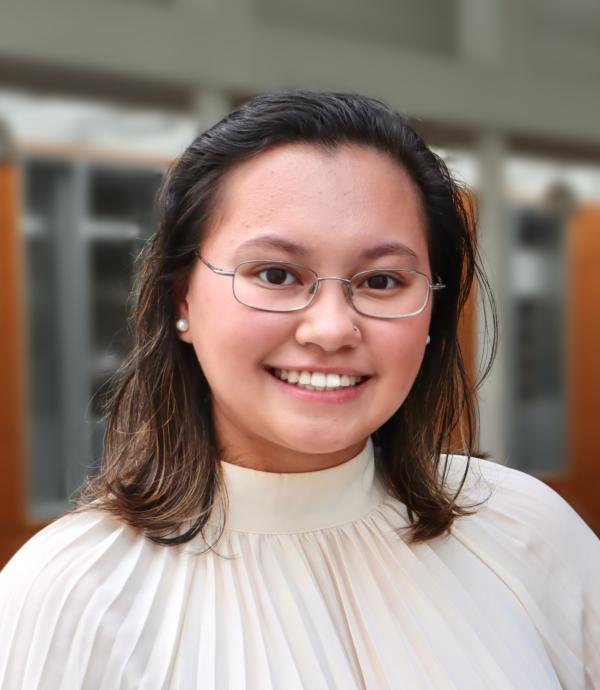 Headshot of young, smiling woman with glasses