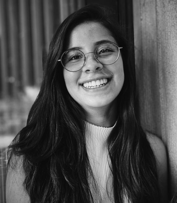 headshot of a young smiling woman with long hair and glasses