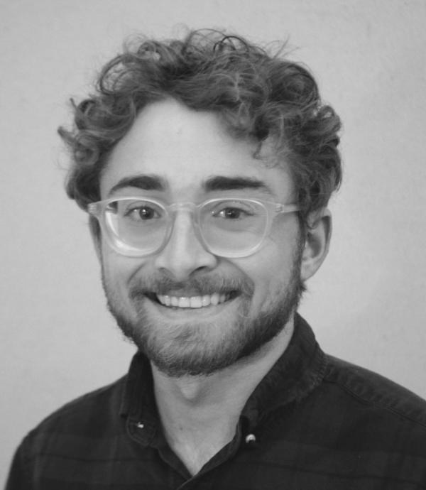 Headshot of young man with glasses, smiling