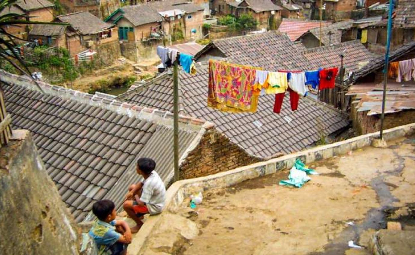 Children sitting along a retaining wall in an informal settlement in Malang, East Java