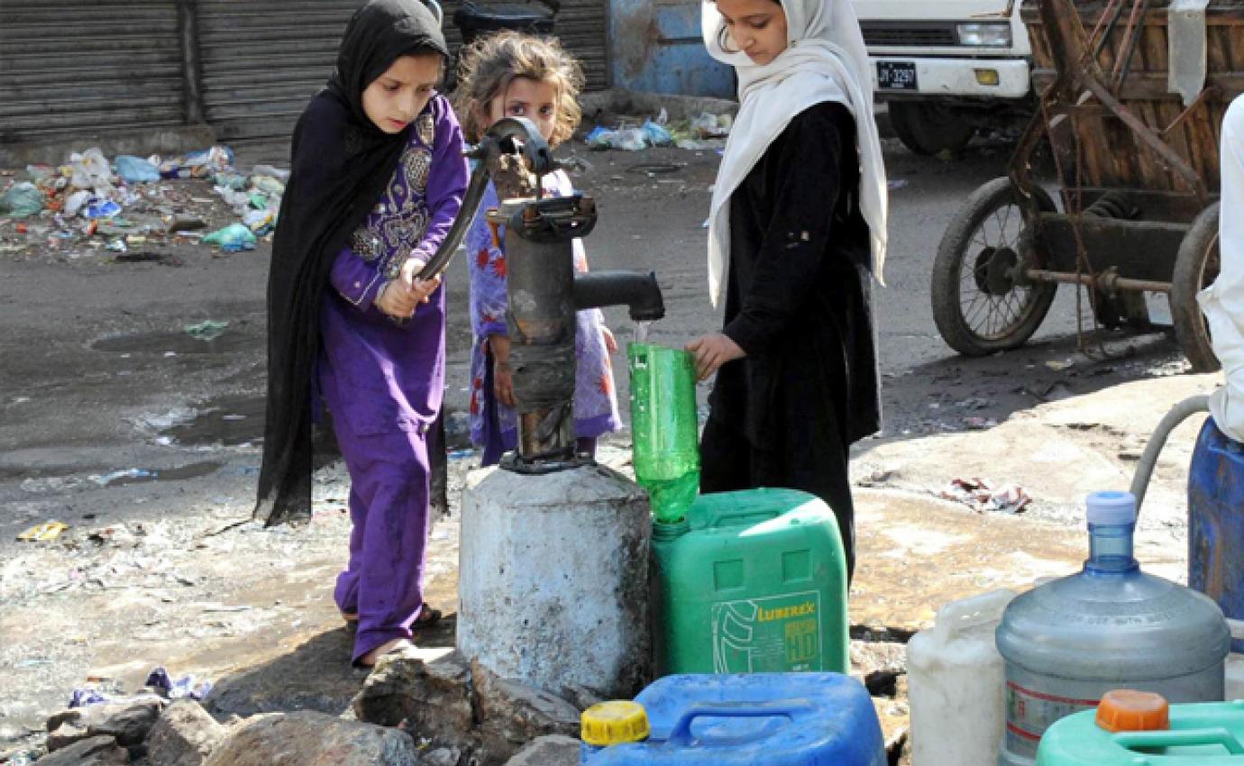 children in Pakistan filling water jugs at a well